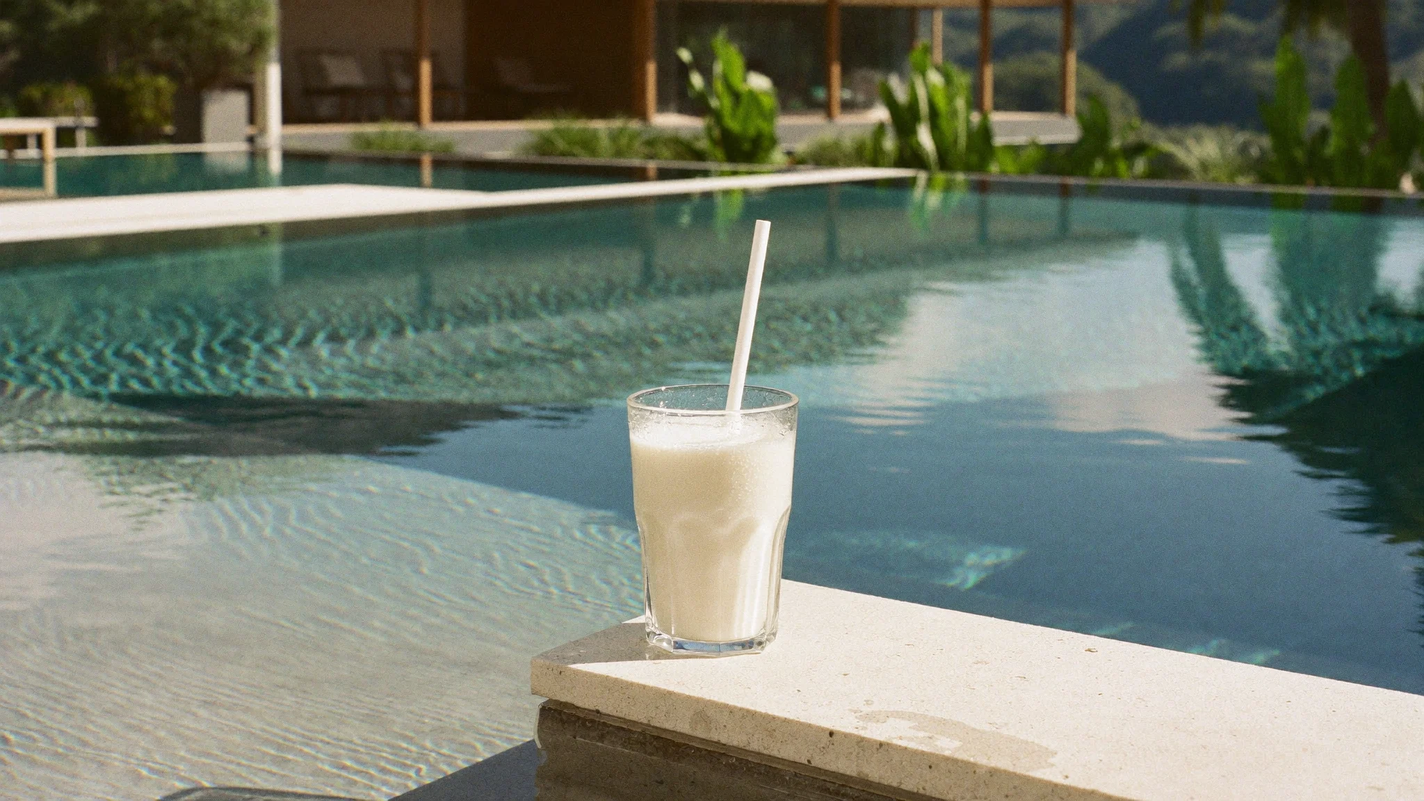 A chilled rice drink beside a sunlit pool