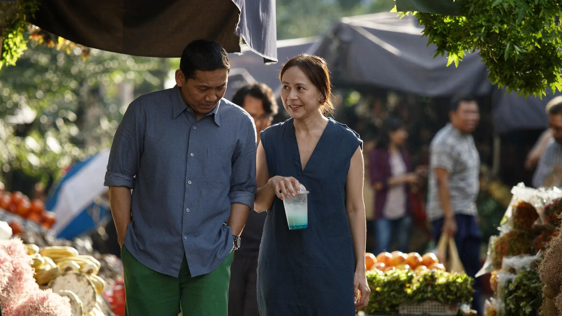 A couple sharing a conversation as they walk through a neighbourhood market